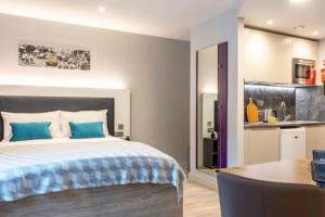 a bedroom with a bed with blue pillows and a kitchen at Central Studios In Lincoln with Free Grab&Go Breakfast in Lincoln