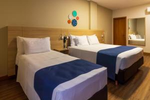 a hotel room with two beds and a mirror at Luds Comfort Hotel in Ponta Grossa +68 photos