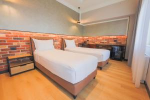 two beds in a room with a brick wall at Hotel Gorenje in Prishtinë