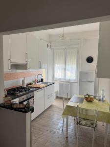 a kitchen with white cabinets and a table and a dining room at Le Casette di Elfo in Grosseto