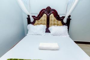 a bed with a wooden headboard and white pillows at Hulcity silver hotel in Kyebando
