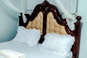 a bed with a wooden headboard and two white pillows at Hulcity silver hotel in Kyebando