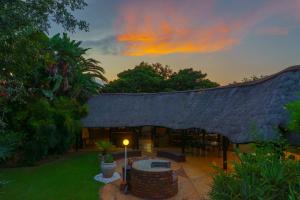 a house with a thatched roof with a patio at Gallery Inn in Bela-Bela