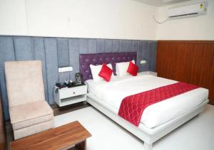 a bedroom with a large bed and a chair at Hotel Orcella in Tirupati