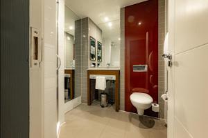a bathroom with a toilet and a red door at Dakota Eurocentral in Motherwell