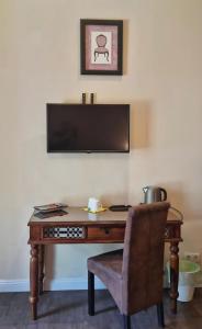 a desk with a chair and a television on a wall at Garden House in Budapest