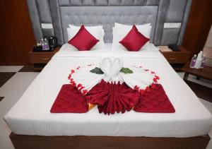 a bed with red and white sheets and red pillows at Hotel Orcella in Tirupati +11 photos