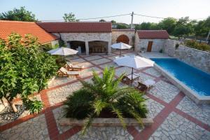 a patio with umbrellas and a swimming pool at Villa Dvori Jokic in Islam Grčki