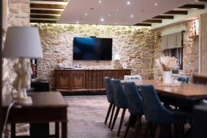 a dining room with a table and a television on a stone wall at Villa Dvori Jokic in Islam Grčki