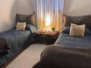 a bedroom with two beds and a table with a lamp at Casita Eureka in San Antonio de Areco