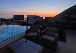 two chairs sitting on top of a balcony with the sunset at Vila Mara in Dhërmi +40 photos