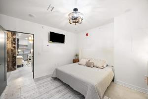 a white bedroom with a bed and a flat screen tv at Park Hotel 1BR Suite 210 in Chattanooga