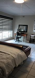 a bedroom with a bed and a desk and window at Meltz Inn in Klerksdorp