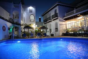 a swimming pool in front of a house at night at Brasilia in Chipiona