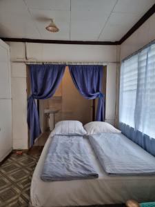 a large bed in a room with blue curtains at Penoria's lodge kubo in Mambajao +28 photos