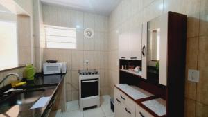 a small kitchen with a stove and a microwave at Casa Miríades in Hortolândia