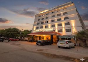 a large white building with cars parked in front of it at Hotel Orcella in Tirupati