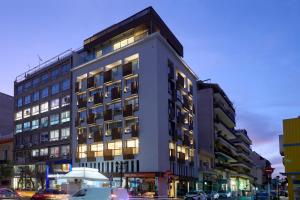 a tall building with cars parked in front of it at Twinn Downtown Piraeus, Santikos Collection in Piraeus