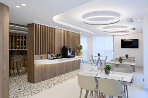 a restaurant with a bar and tables and chairs at Twinn Downtown Piraeus, Santikos Collection in Piraeus