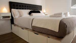 a large bed with white sheets and pillows on it at Ecos de Mar Refugios in Puerto Pirámides