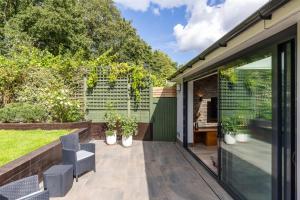 a garden room with a patio with chairs and plants at Apartment in Guildford with Parking in Stoughton