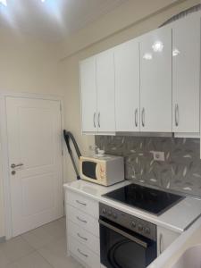 a kitchen with white cabinets and a microwave at Apartament Oresti in Korçë +9 photos