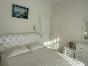 a white bedroom with a white bed with a picture on the wall at Apartament Oresti in Korçë