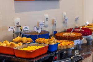 a buffet filled with different types of cakes and pies at Luds Comfort Hotel in Ponta Grossa