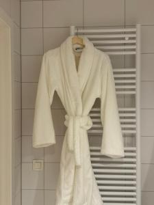 a white robe hanging on a rack in a bathroom at L'Excelsior Suites in Brasschaat +49 photos