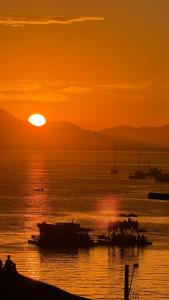 a sunset over a body of water with boats at Cabana no Morro do Macaco in Bombinhas