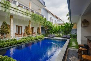 a pool in the courtyard of a building with chairs and tables at Kayuma House Canggu in Canggu