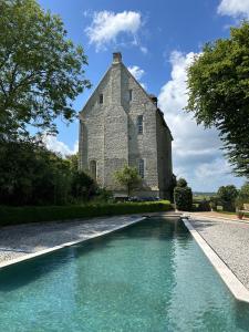 a building with a swimming pool in front of it at CHATEAU DE MONFREVILLE in Monfréville