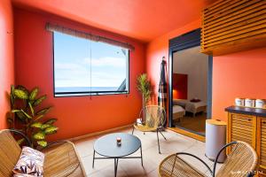 a living room with orange walls and a table and chairs at Koté La Savan' in Saint-Paul