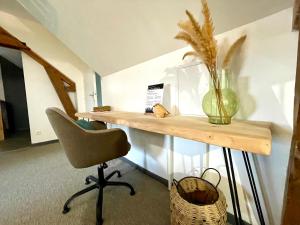 a desk with a chair and a vase on it at L'Appart'Anjou in Cantenay-Épinard