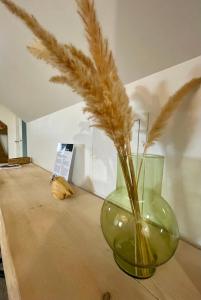 a green vase with grass in it on a table at L'Appart'Anjou in Cantenay-Épinard