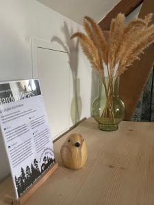 a wooden table with a book and a vase with feathers at L'Appart'Anjou in Cantenay-Épinard
