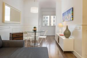 a white living room with a glass table and chairs at Enjoybcn Coliseum Apartments in Barcelona