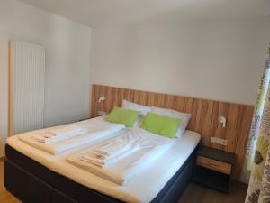 a bed with white sheets and green pillows at Gasthof zur Post in Lalling