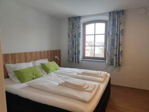 a bed with two green pillows and a window at Gasthof zur Post in Lalling