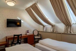 a bedroom with two beds and a desk and a television at Hotel Ptuj in Ptuj