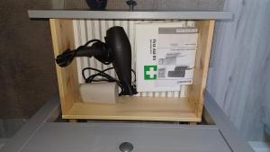 a black hair dryer in a box on a shelf at Logement à 5 min du parc Astérix in Plailly +1 photo