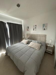 a bedroom with a large bed with a gray blanket at Arenas Gutyn Ebrill in Puerto Madryn