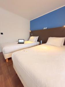 two beds in a hotel room with a clock on it at Kyriad Blois Sud - Vineuil in Vineuil