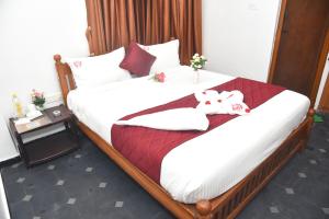 a bedroom with a large bed with white sheets and red pillows at RD Hotel-Near Anna Statue in Perundurai
