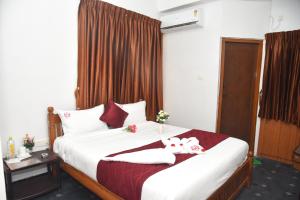 a bedroom with a bed with two towels on it at RD Hotel-Near Anna Statue in Perundurai