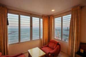 a room with large windows with a chair and a table at THE SEASHORE HOTEL in Kanyakumari