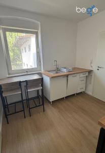 a kitchen with a sink and a table and a window at BEGE APARTMENTS BalanceBase in Philippsburg