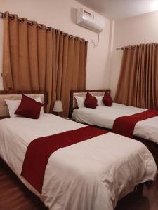 a bedroom with two beds with red and white sheets at Hotel Lisne jungle land in Bharatpur