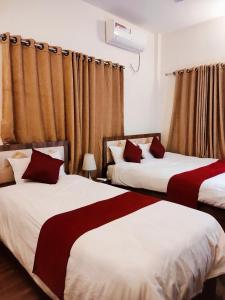 two beds in a hotel room with curtains at Hotel Lisne jungle land in Bharatpur