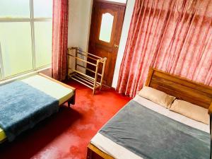 a bedroom with two beds and a window at Siloneeds HOSTEL in Nuwara Eliya